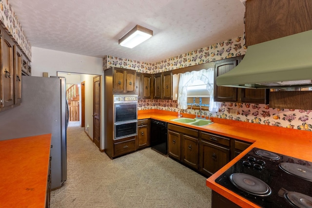 kitchen with a sink, black appliances, premium range hood, light countertops, and a textured ceiling