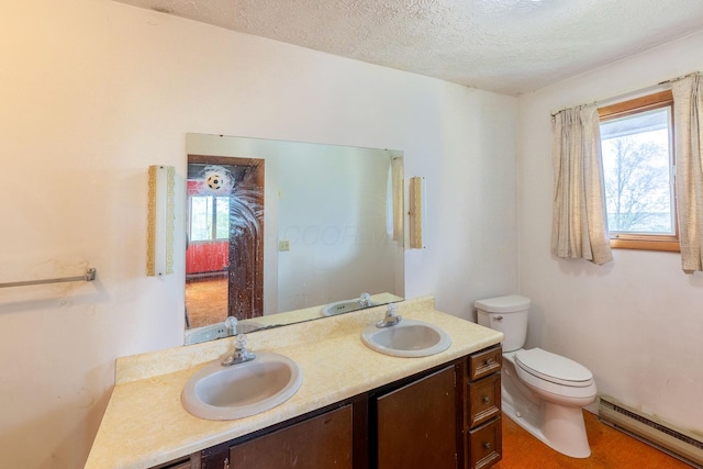 bathroom with baseboard heating, toilet, double vanity, and a textured ceiling