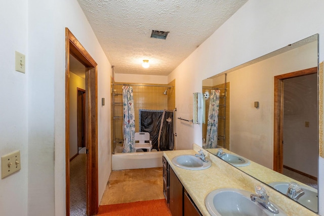 bathroom with a textured ceiling, shower / bath combo, and double vanity