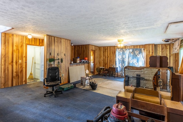 carpeted living room featuring wood walls, a textured ceiling, healthy amount of natural light, and a ceiling fan