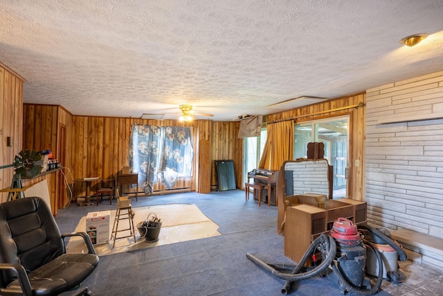 living area featuring a textured ceiling, wooden walls, and a ceiling fan
