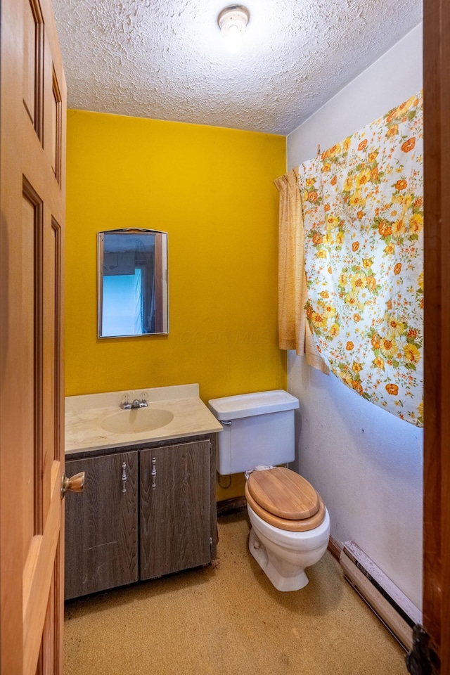 half bath with baseboard heating, toilet, a textured ceiling, and vanity