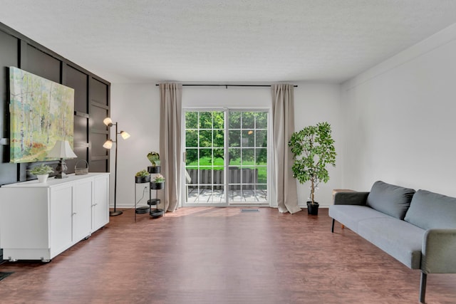 living area with wood finished floors, a textured ceiling, and baseboards