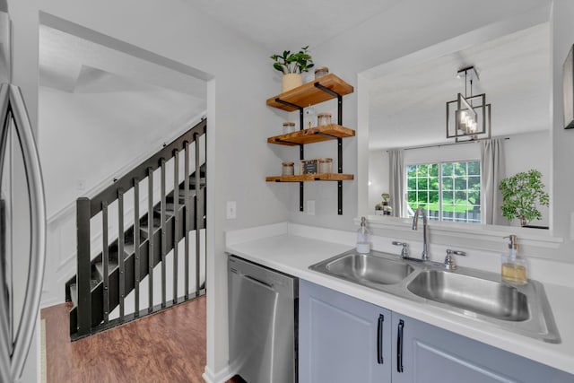 kitchen featuring appliances with stainless steel finishes, a sink, dark wood-style flooring, open shelves, and light countertops