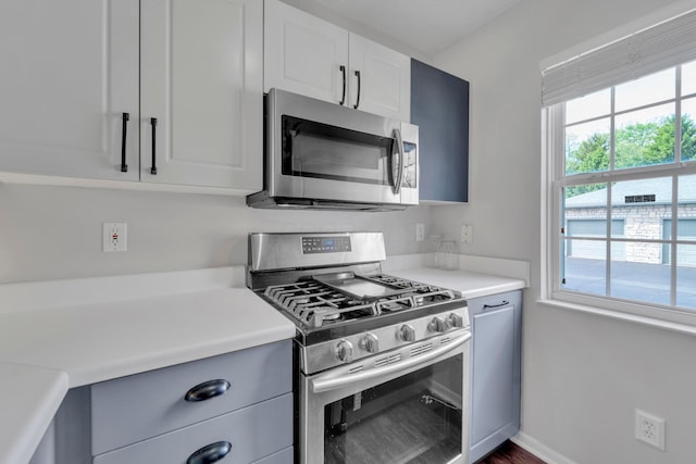 kitchen featuring appliances with stainless steel finishes, light countertops, baseboards, white cabinets, and dark wood-type flooring