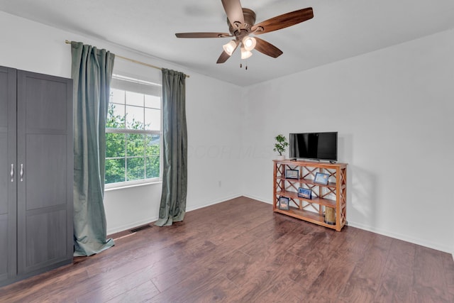 empty room with a ceiling fan, wood finished floors, and baseboards