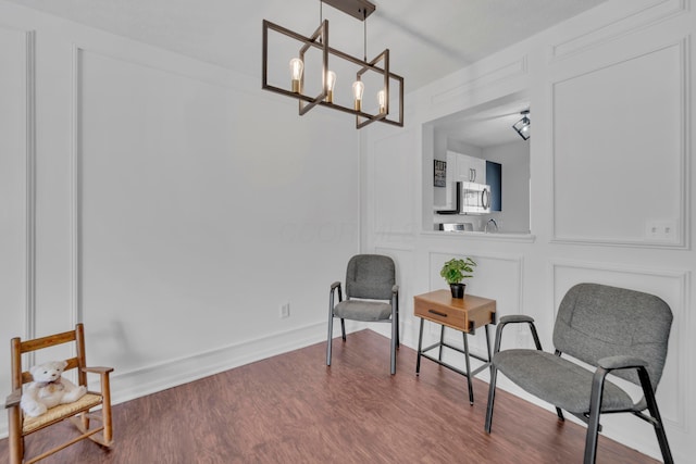 living area with a chandelier, dark wood-type flooring, and baseboards