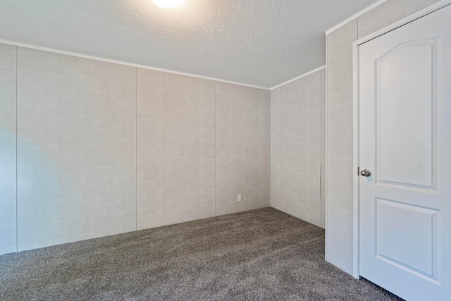 spare room featuring dark colored carpet, a textured ceiling, and ornamental molding