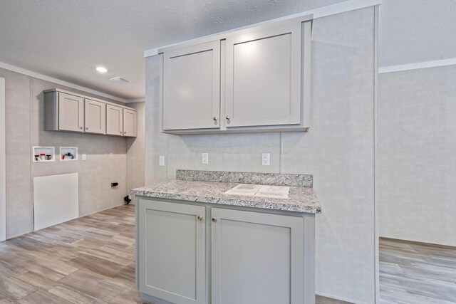 washroom featuring washer hookup, cabinet space, light wood-style floors, hookup for an electric dryer, and a textured ceiling