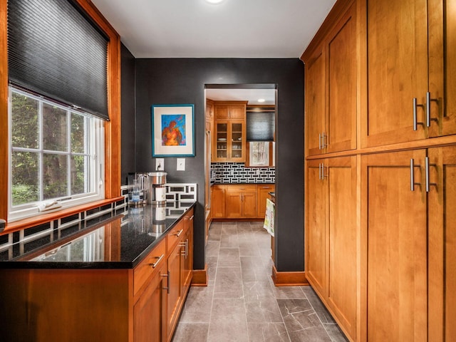 10 Park Dr, Columbus, OH 43209 - kitchen with brown cabinetry, tasteful backsplash, dark stone counters, and glass insert cabinets