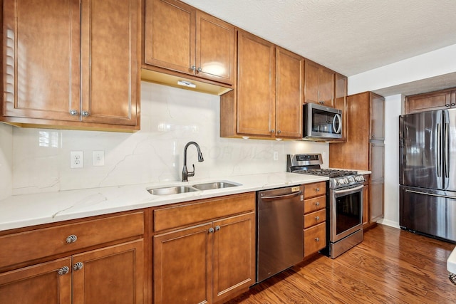 1753 Chestnut Farms Loop, Grove City, OH 43123 - kitchen featuring stainless steel appliances, a sink, wood finished floors, brown cabinets, and tasteful backsplash