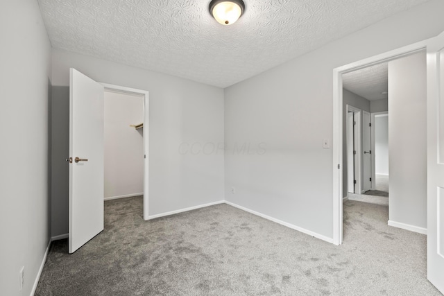 2458 Dunsworth Dr, Columbus, OH 43235 - unfurnished bedroom featuring carpet flooring, a textured ceiling, a walk in closet, and baseboards