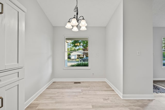 2458 Dunsworth Dr, Columbus, OH 43235 - unfurnished dining area with plenty of natural light, a chandelier, light wood finished floors, baseboards, and a textured ceiling