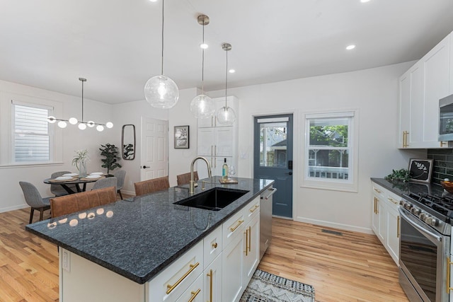 549 Hanford St, Columbus, OH 43206 - kitchen with a sink, stainless steel appliances, light wood finished floors, white cabinetry, and decorative light fixtures