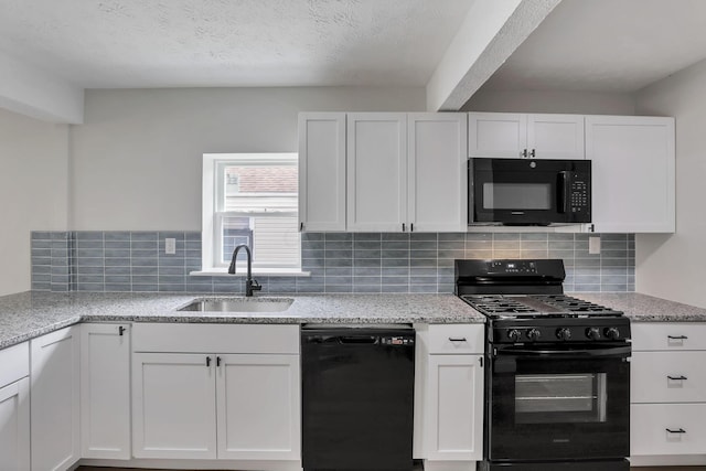 kitchen with black appliances, a sink, white cabinets, and light stone countertops