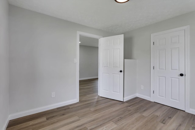 unfurnished bedroom featuring wood finished floors and baseboards