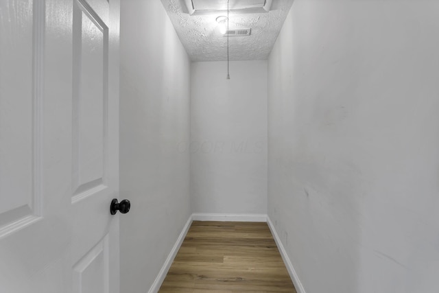 walk in closet with wood finished floors and attic access