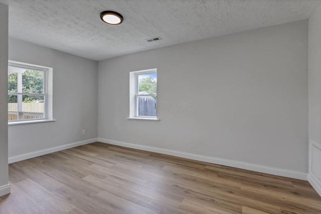unfurnished room with wood finished floors, baseboards, and a textured ceiling