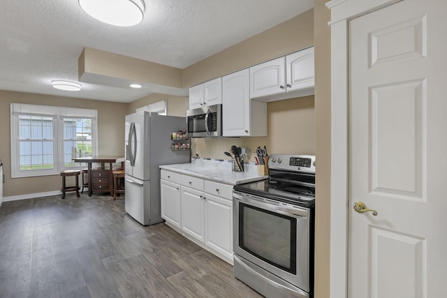 11708 Broad St, Millersport, OH 43046 - kitchen with appliances with stainless steel finishes, white cabinets, a textured ceiling, dark wood-style floors, and baseboards