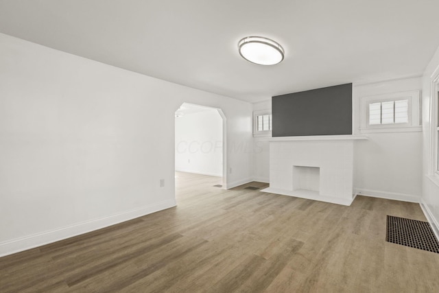 436 Nashoba Ave, Columbus, OH 43223 - unfurnished living room with arched walkways, baseboards, a brick fireplace, and wood finished floors