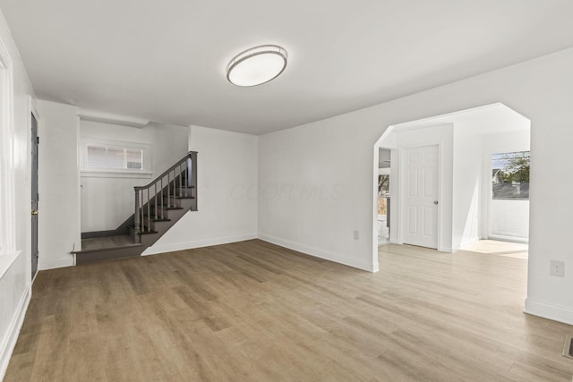 436 Nashoba Ave, Columbus, OH 43223 - unfurnished living room featuring wood finished floors, stairs, baseboards, and arched walkways