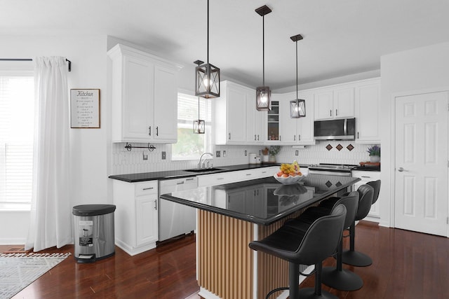 210 Carson Ct, Pickerington, OH 43147 - kitchen featuring stainless steel appliances, a sink, dark countertops, dark wood-style flooring, and a breakfast bar area