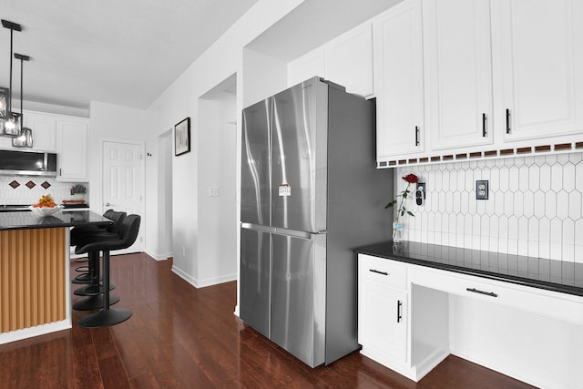 210 Carson Ct, Pickerington, OH 43147 - kitchen featuring appliances with stainless steel finishes, dark countertops, a breakfast bar area, decorative backsplash, and dark wood-type flooring