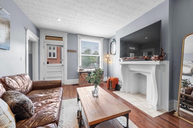 915 Dennison Ave, Columbus, OH 43201 - living room featuring wood finished floors, baseboards, a textured ceiling, and a fireplace with flush hearth