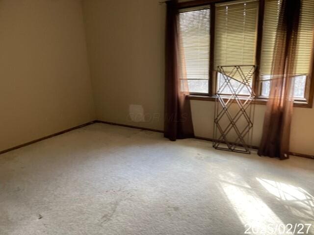 unfurnished room featuring light carpet, plenty of natural light, and baseboards