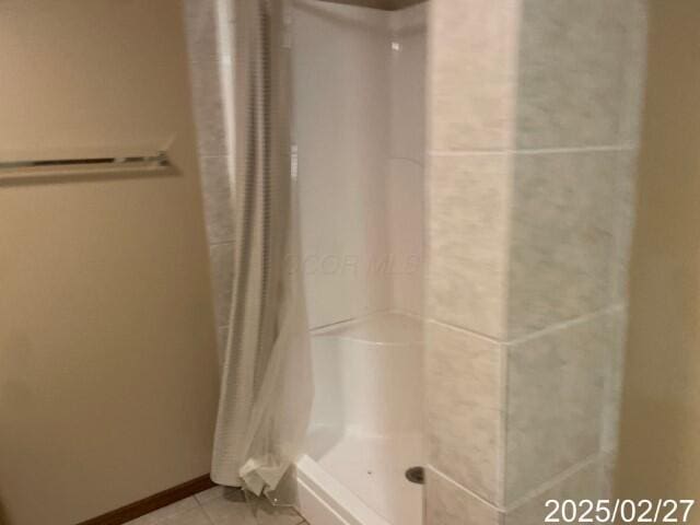 full bath with a shower stall, tile patterned flooring, and baseboards