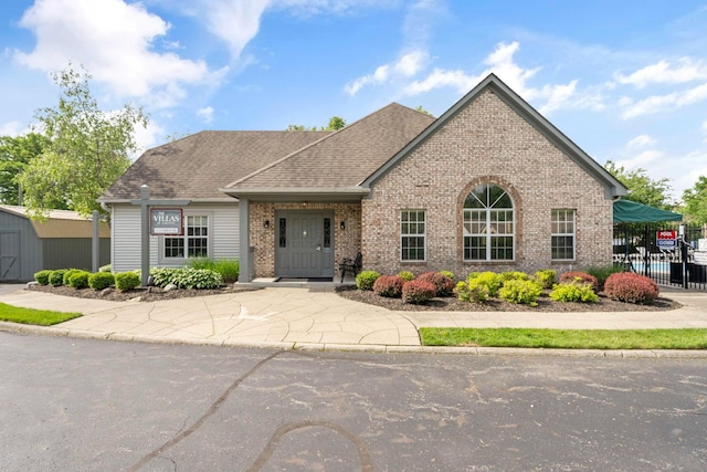1272 Villa Oaks Ct, Columbus, OH 43230 - view of front of property with brick siding, a storage unit, an outdoor structure, fence, and a shingled roof