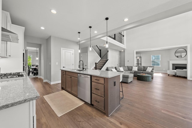 kitchen featuring stainless steel appliances, a sink, a center island with sink, dark wood-style flooring, and open floor plan