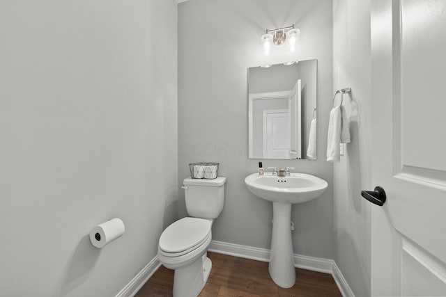 bathroom with toilet, baseboards, and wood finished floors