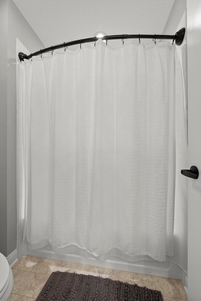bathroom with shower / tub combo, toilet, and baseboards