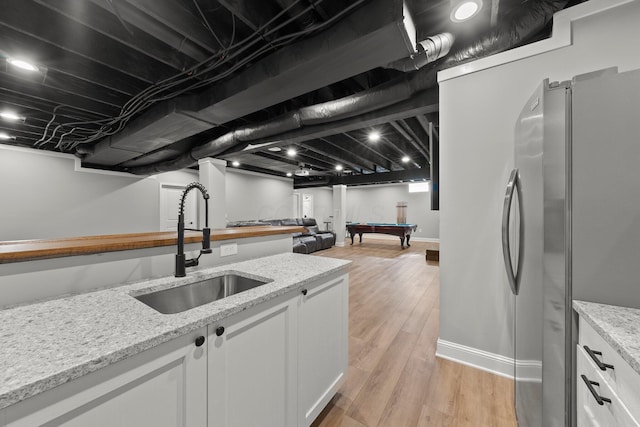 kitchen with freestanding refrigerator, a sink, white cabinets, light wood finished floors, and billiards table