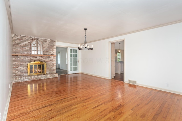 26976 Jackson Rd, Circleville, OH 43113 - unfurnished living room featuring a chandelier, wood finished floors, baseboards, a brick fireplace, and ornamental molding