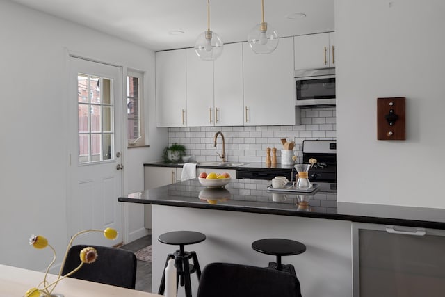 1809 NW Ct Unit E, Columbus, OH 43212 - kitchen with appliances with stainless steel finishes, a kitchen breakfast bar, tasteful backsplash, dark countertops, and white cabinetry