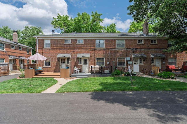 1809 NW Ct Unit E, Columbus, OH 43212 - view of front of house featuring brick siding, a front yard, a chimney, and a wooden deck