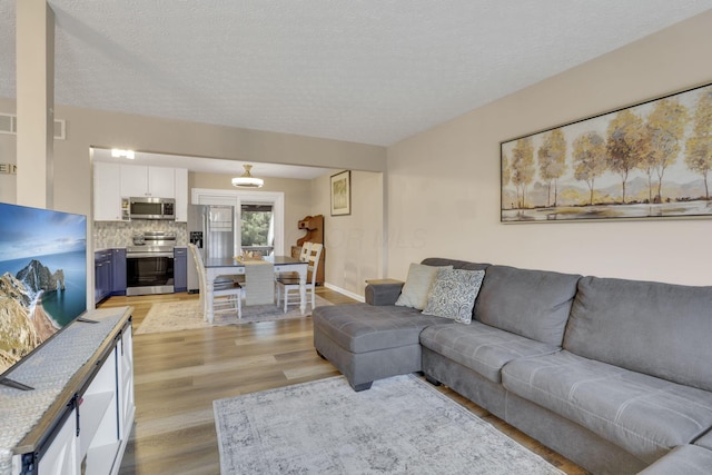 4292 Nipigon Dr, Columbus, OH 43207 - living area with light wood-type flooring, a textured ceiling, baseboards, and a chandelier