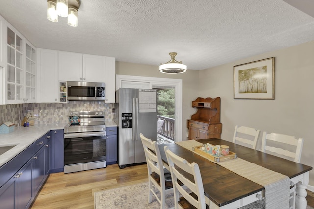 4292 Nipigon Dr, Columbus, OH 43207 - kitchen with appliances with stainless steel finishes, blue cabinets, light wood-style flooring, light countertops, and decorative backsplash