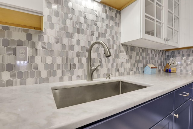 4292 Nipigon Dr, Columbus, OH 43207 - kitchen with blue cabinetry, a sink, backsplash, glass insert cabinets, and white cabinetry