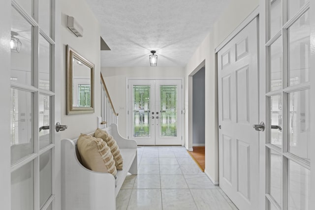 entryway featuring french doors, light tile patterned floors, a textured ceiling, stairs, and baseboards