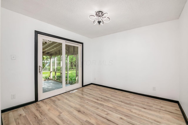 spare room featuring wood finished floors, a textured ceiling, and baseboards