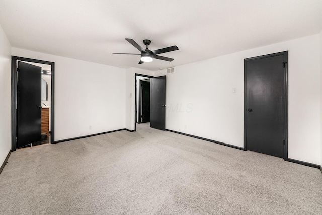 unfurnished bedroom featuring light colored carpet, baseboards, a ceiling fan, and ensuite bath