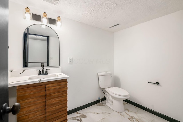 bathroom featuring marble finish floors, toilet, a textured ceiling, vanity, and baseboards