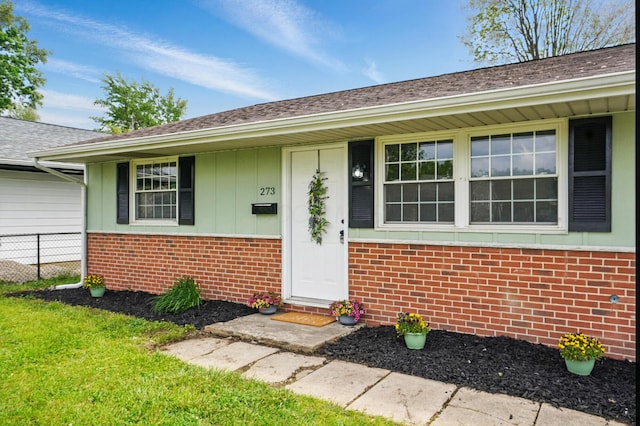 273 E Alcott Rd, Columbus, OH 43207 - view of exterior entry featuring brick siding, a shingled roof, and board and batten siding