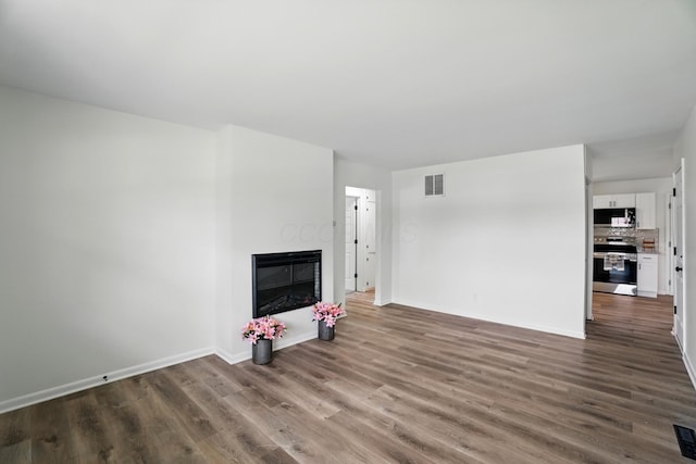 273 E Alcott Rd, Columbus, OH 43207 - unfurnished living room with wood finished floors, a glass covered fireplace, and baseboards