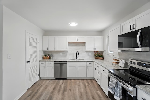 273 E Alcott Rd, Columbus, OH 43207 - kitchen with appliances with stainless steel finishes, a sink, white cabinets, and decorative backsplash