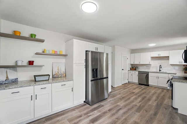 273 E Alcott Rd, Columbus, OH 43207 - kitchen featuring open shelves, appliances with stainless steel finishes, white cabinets, a sink, and light stone counters