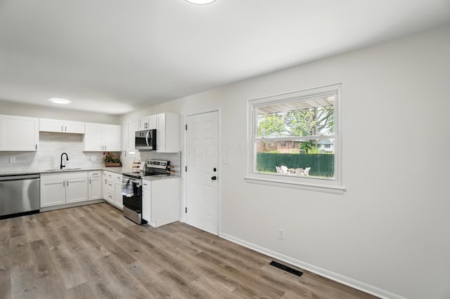 273 E Alcott Rd, Columbus, OH 43207 - kitchen featuring stainless steel appliances, a sink, white cabinetry, decorative backsplash, and light wood finished floors